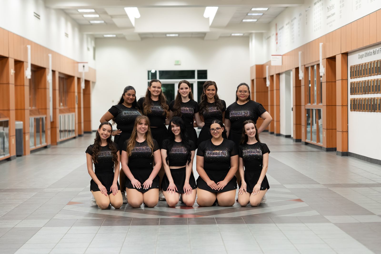 Dance team in sparkly Cougars shirts posed in a school hallway