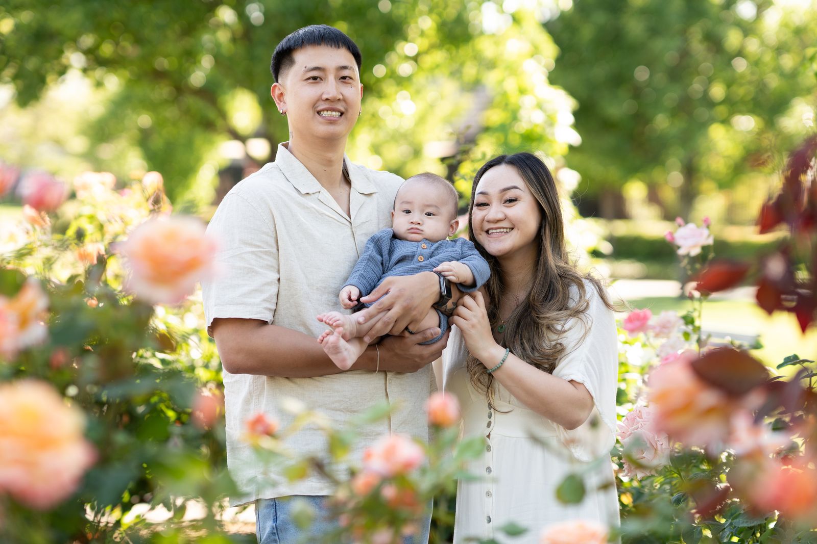 Parents holding their baby in a rose garden