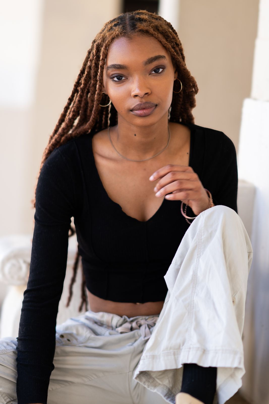 Woman with auburn braids seated in soft natural light